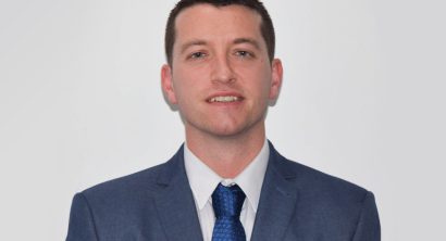 Martyn Jones in suit smiling at camera in front of white backdrop