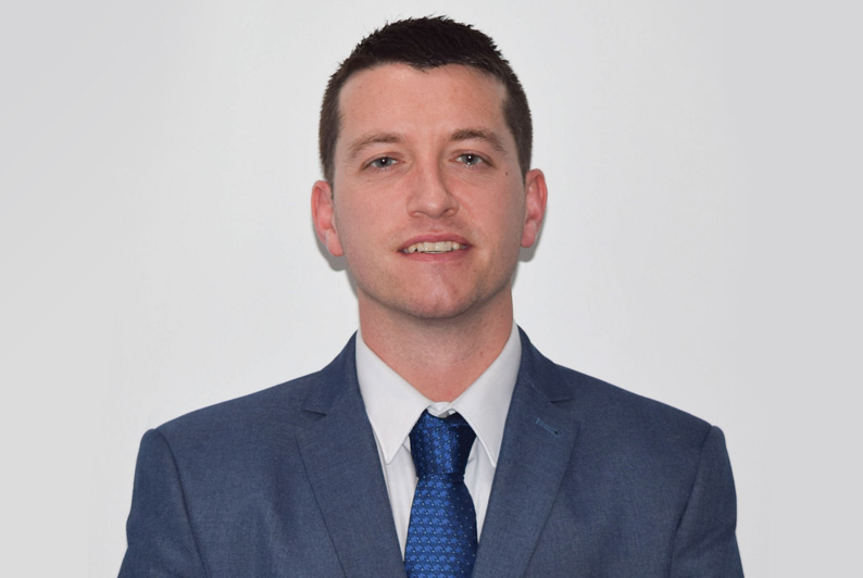 Martyn Jones in suit smiling at camera in front of white backdrop